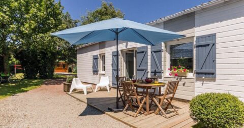 maison de plein pied avec bardage en bois peint en blanc, volet en bois gris, terrasse en bois et allée gravillonnée