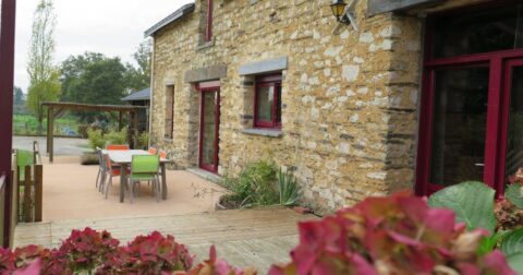 longère en pierre avec linteaux de fenêtre en ardoise, huisseries rouges, terrasse et pergola métallique