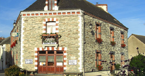 Grande maison hôtel de bourg en pierre, avec contour des portes et fenêtres en alternance de briques blanches et rouges