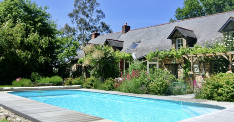 grande longère en pierre avec jardin et pergola très fleurie donnant une piscine