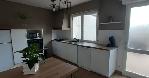 cuisine d'appartement avec meuble blanc et plan de travail en bois, table en bois et décoration épurée