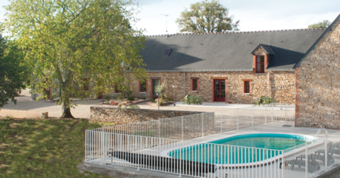 Longère en pierre avec embrasement de portes et fenêtres en brique rouge et piscine protégée par une barrière blanche