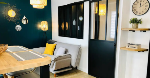 studio chic et design avec porte et verrière métallique, murs bleu canard et décoration en osier et jeu de miroir de formes différentes