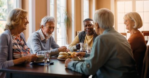 groupe de 5 retraités déjeunant autour d'une table