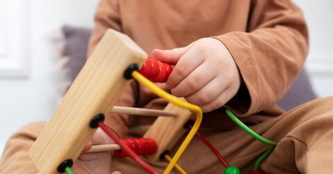 petit garçon jouant avec un boulier en bois