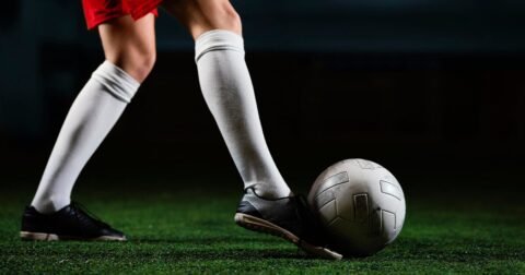 femme en tenue de foot tapant dans un ballon