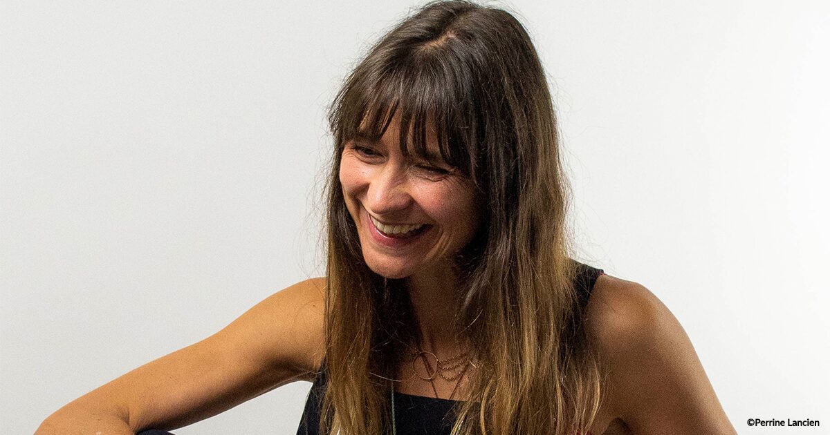 Femme aux cheveux longs châtains de 3/4 rigolant