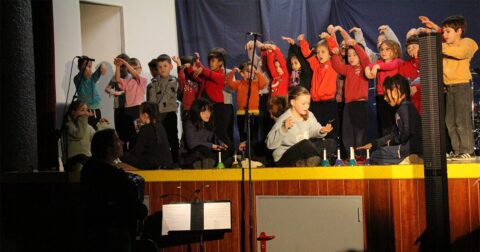 groupe d'enfants en t-shirt rouge chantant sur scène