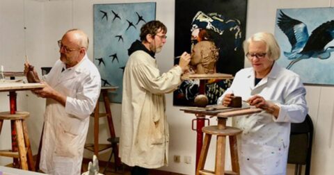 3 artistes debout dans un atelier de peinture et sculpture