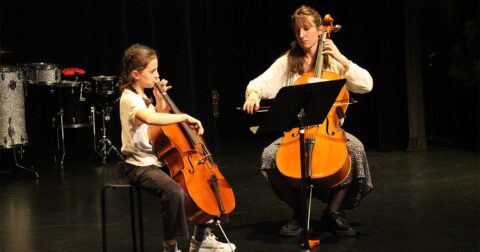 Professeure de violoncelle sur scène avec sa jeune élève