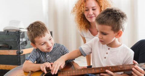 une femme regardant deux petits garçons jouer de la guitare ensemble