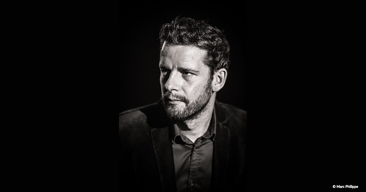 Portait noir et blanc d'une homme avec cheveux courts, barbe et costume