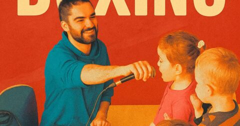 Un homme souriant tend un micro à deux enfants
