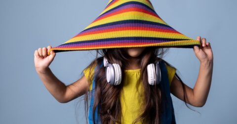 jeune fille avec tissus coloré sur la tête qui cache ses yeux et un casque autour du cou