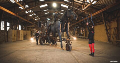 cheval articulé en métal guidé par des artistes dans une carrière couverte