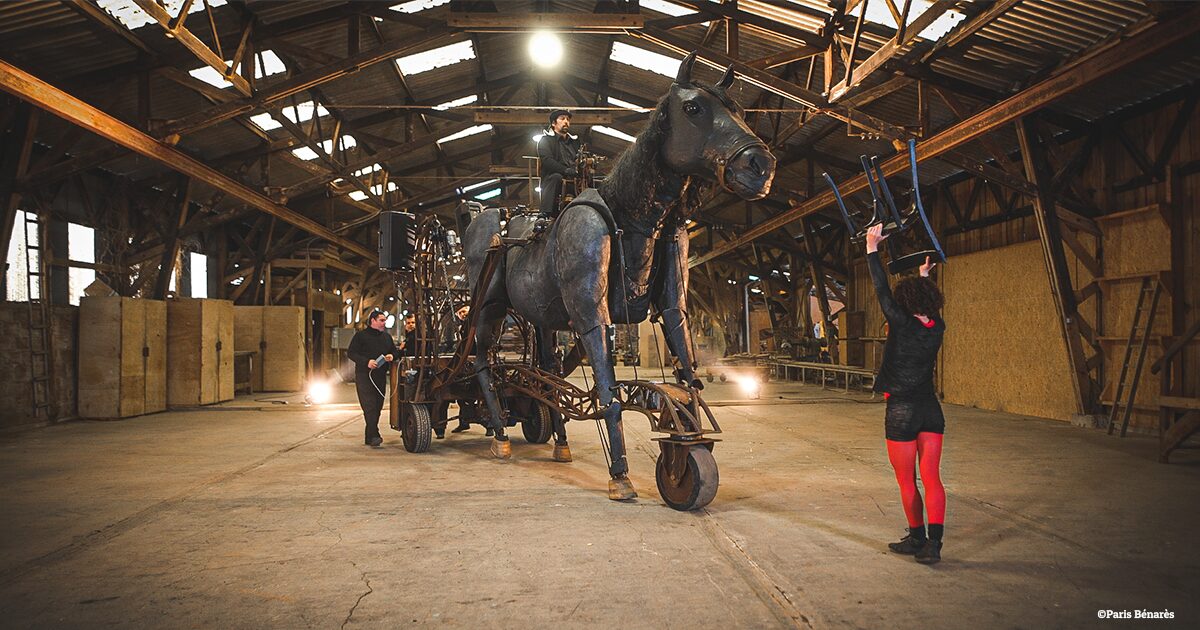 cheval articulé en métal guidé par des artistes dans une carrière couverte
