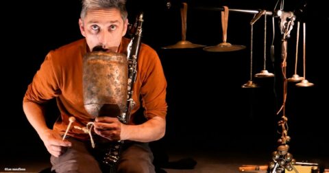 musicien sur scène soufflant dans une cloche en métal