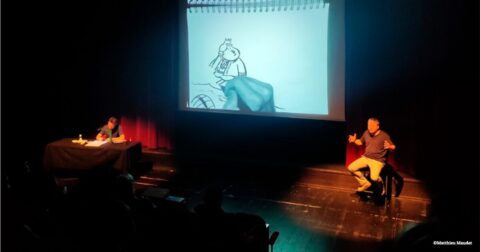un artiste sur scène dessinant devant un écran géant et l'autre contant l'histoire