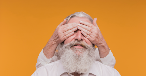 homme âgé dont les yeux sont cachés par les mains d'une personne derrière lui