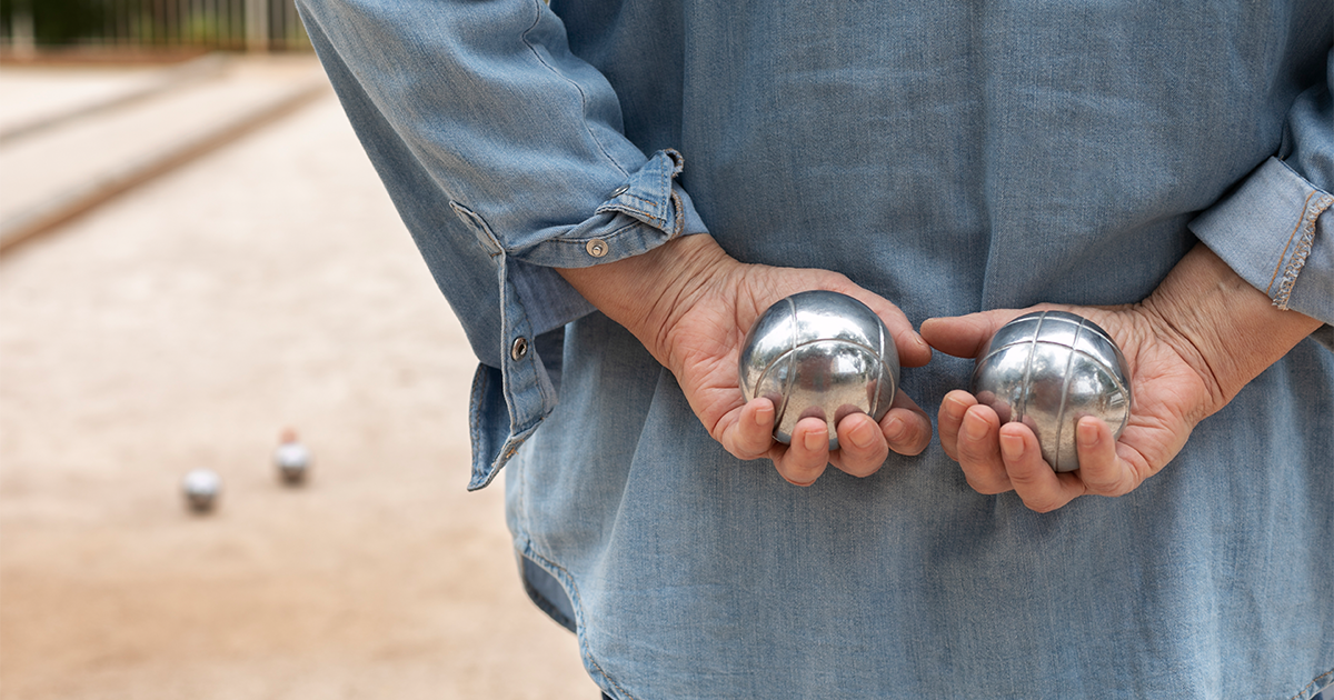 femme sénior de dos tenant des boules de pétanque