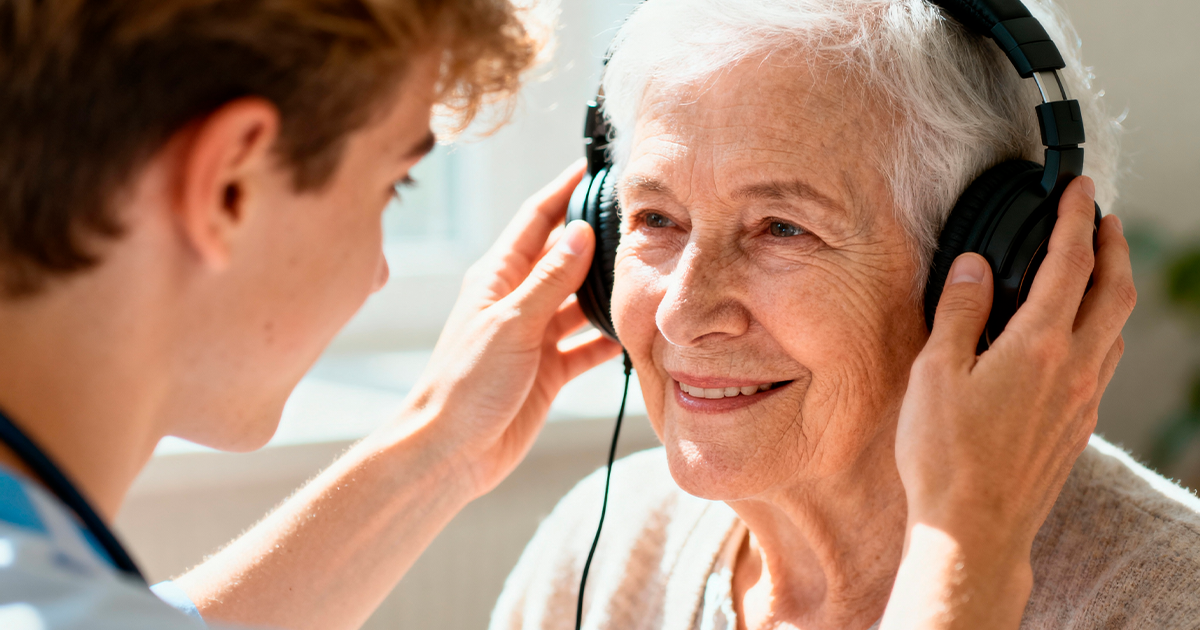 Retraitée assistée d'un personne lui posant un casque audio sur la tête