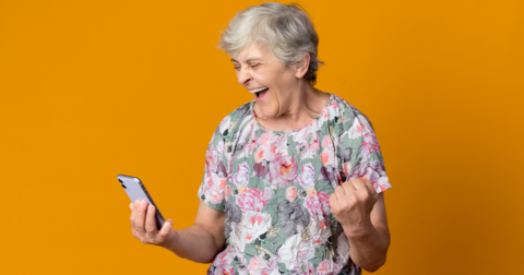 Une sénior manifestant de la fierté en utilisant son téléphone portable