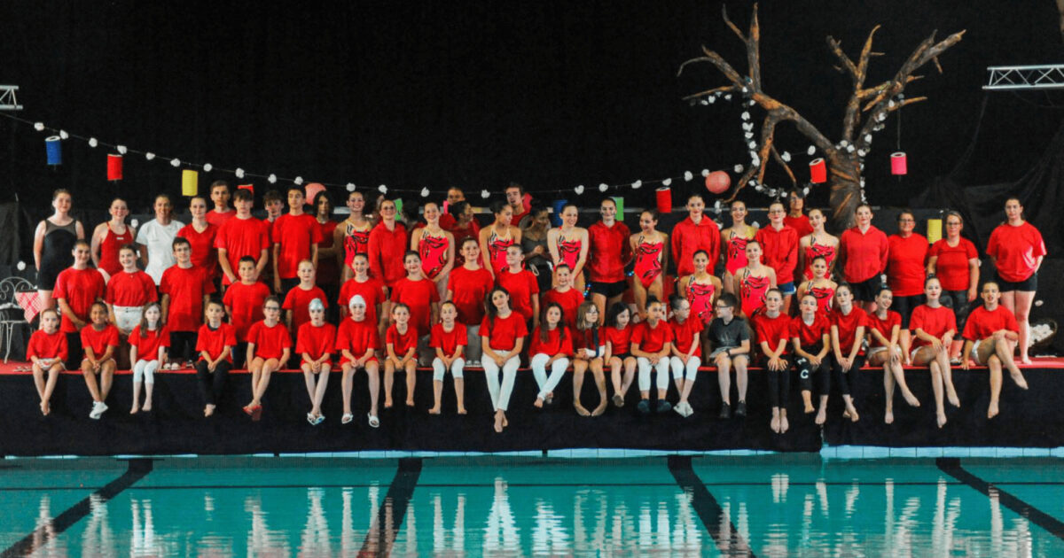 groupe de nageurs en tenues rouges posant au bord du bassin de natation