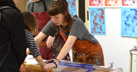 jeune femme en tablier de protection lors d'un atelier de sérigraphie