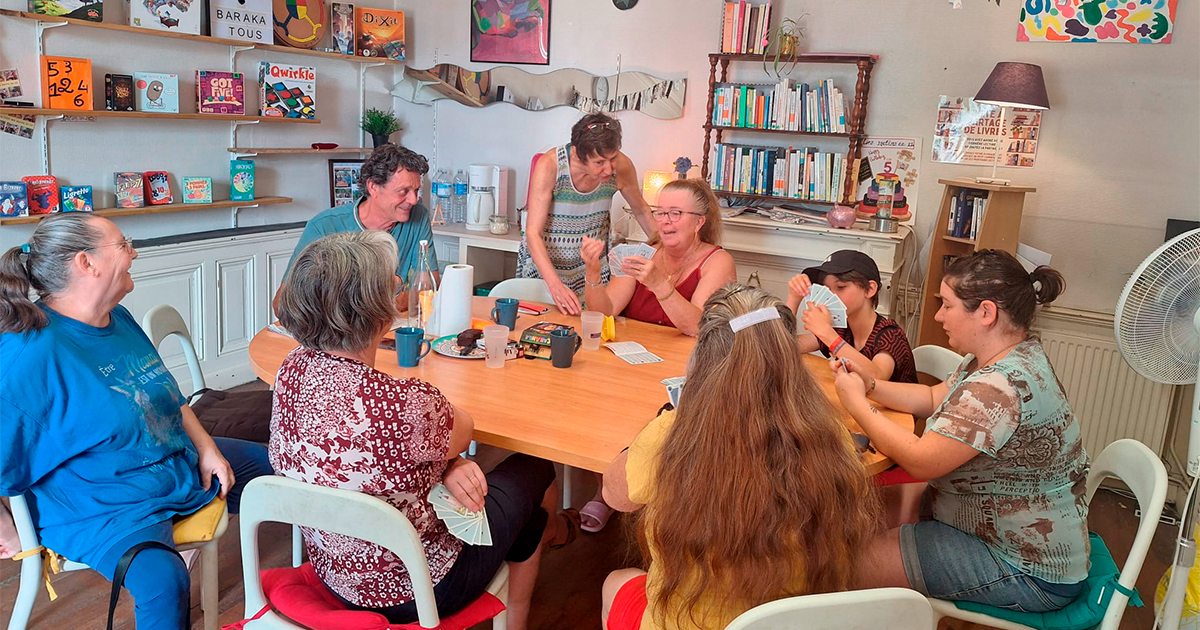 adultes et enfants autour d'une table jouant à des jeux de cartes en rigolant