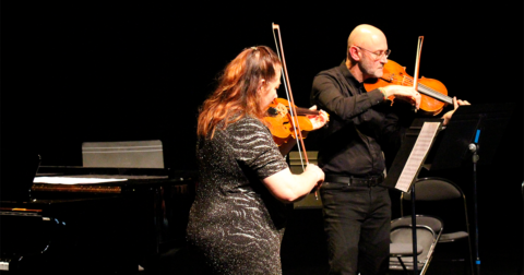 deux violonistes, hun homme et une femme, debout sur scène