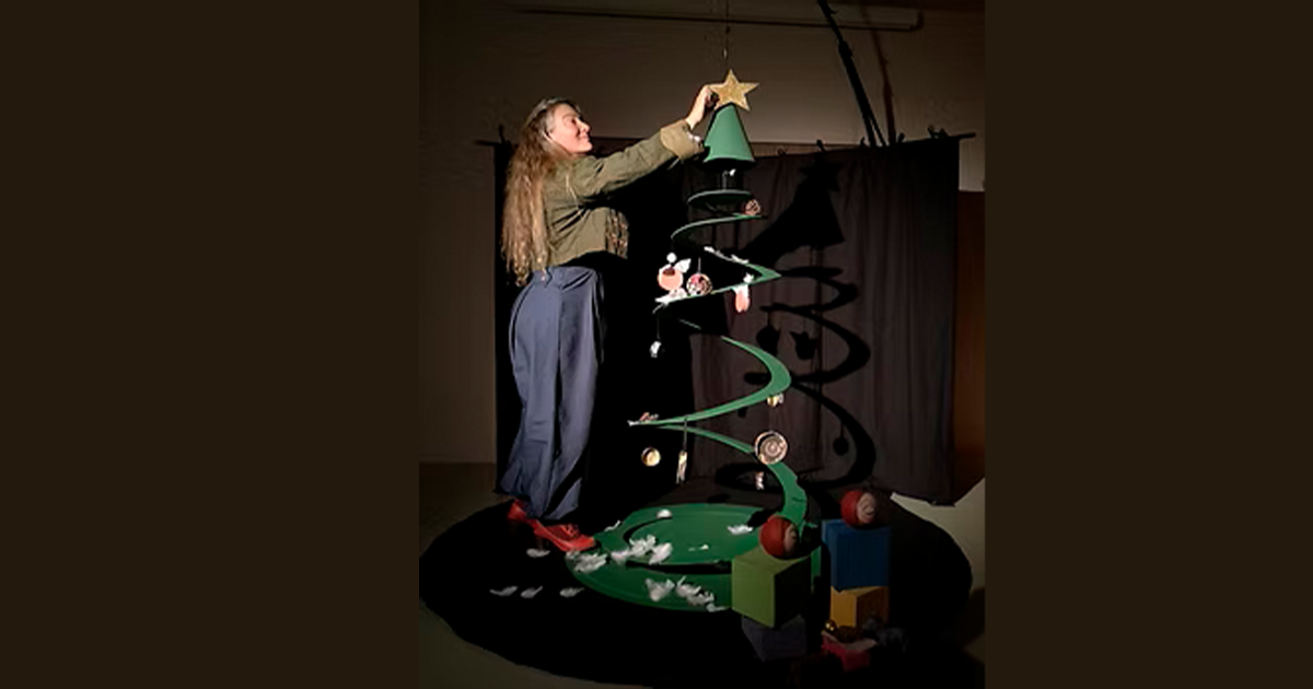 femme debout sur un petit escabeau accrochant des décorations dans son sapin de Noël