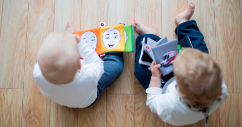 deux bébés vue d'en haut qui regardent un livre coloré